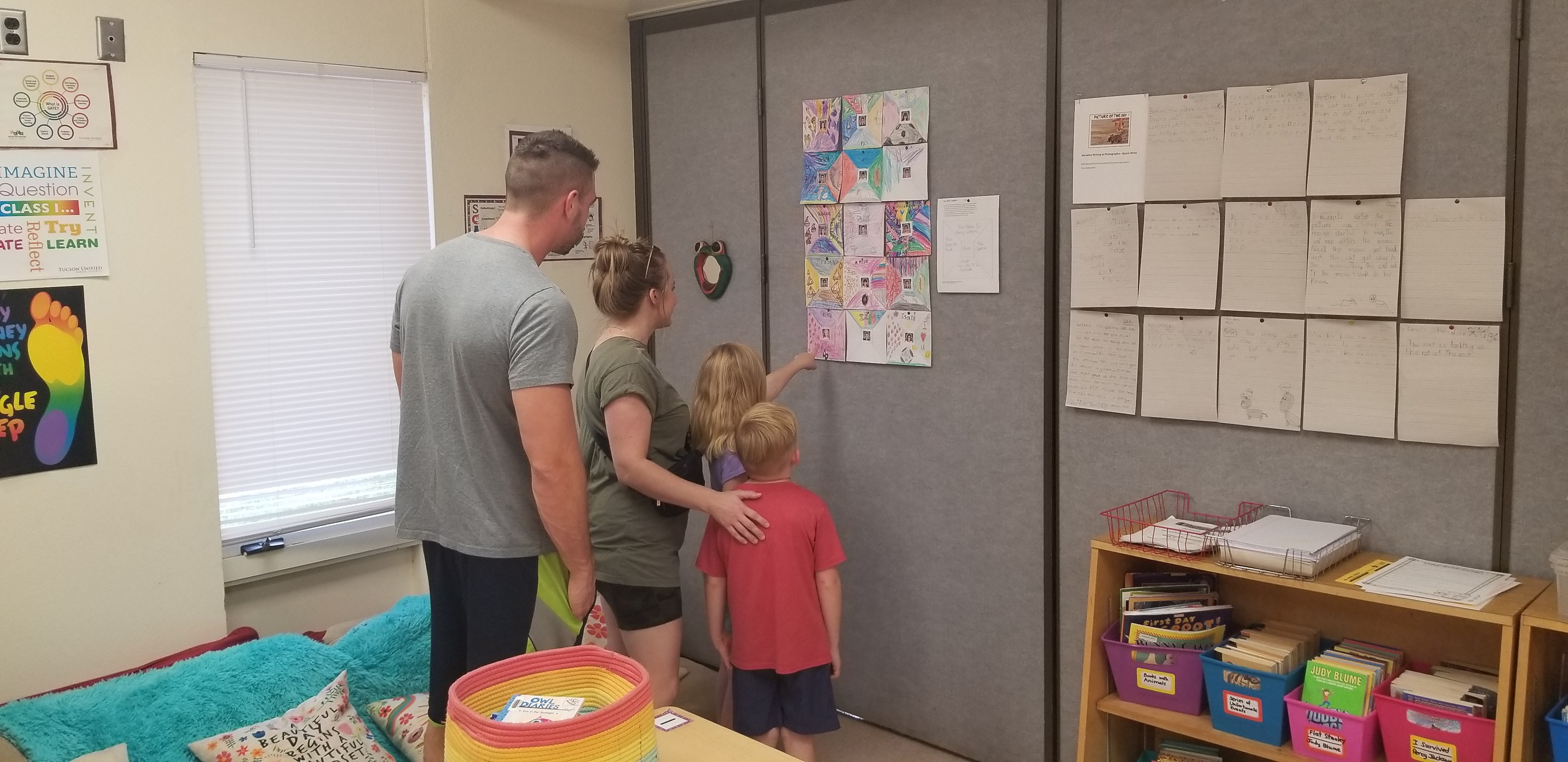 Two students point out their artwork to their parents