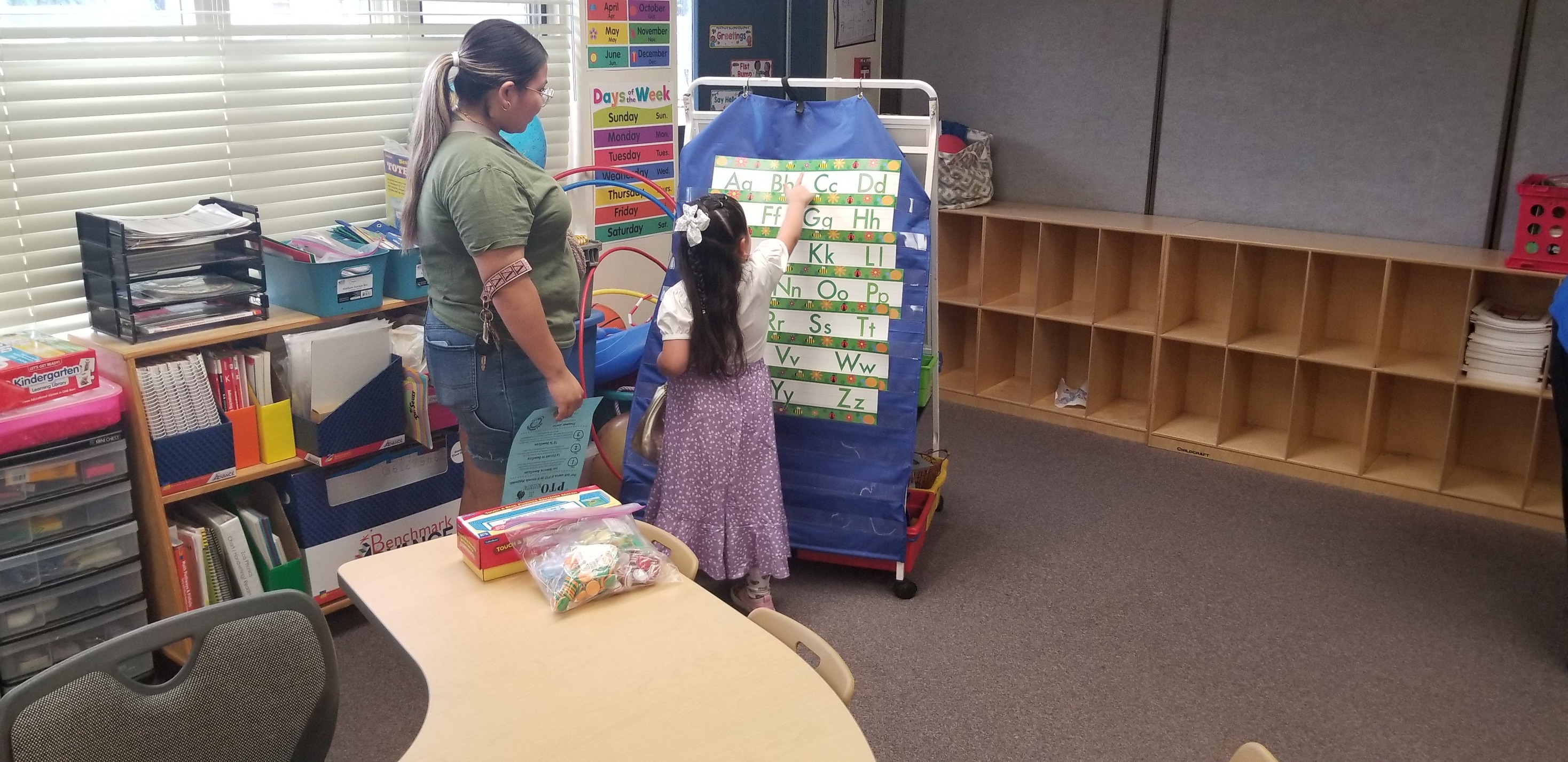 A little girl shows her mom a chart in the classroom