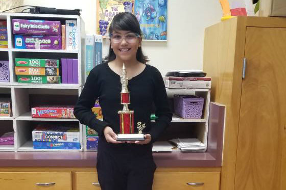 A girl smiles with her trophy