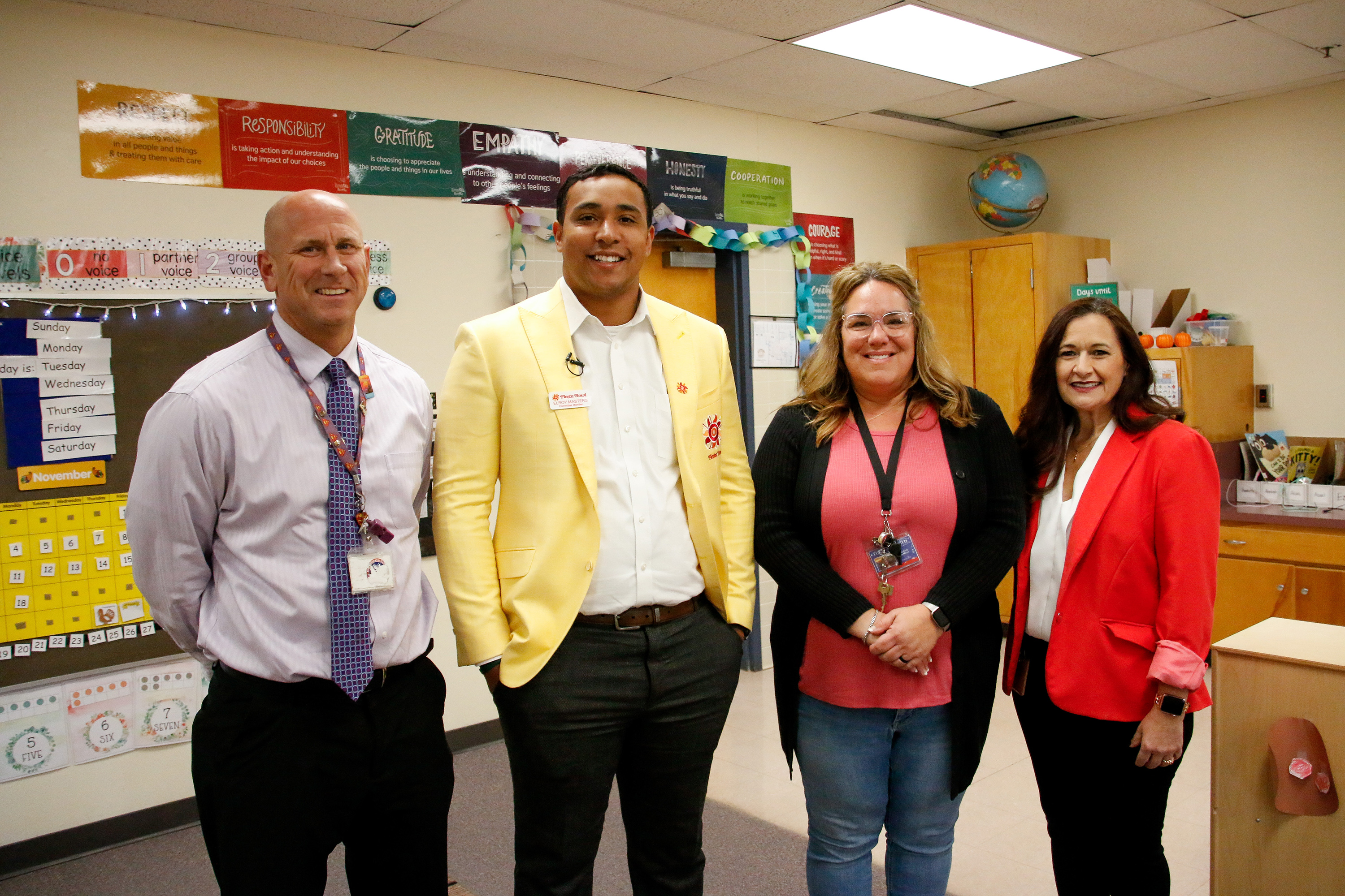 Two men and two women pose for a photo in a classroom