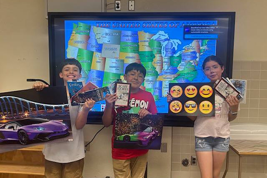 Three students hold up posters they won in the geography bee