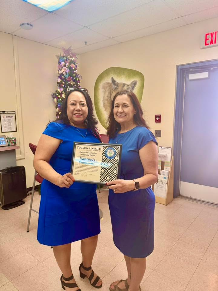 Two women smile, holding a certificate