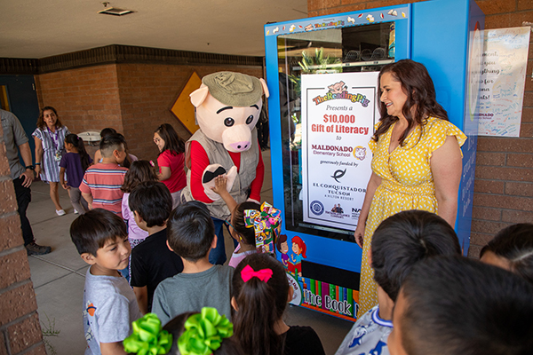 A man in a pig costume gives students high-fives