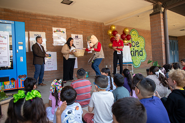 A man dressed in a pig costume reaches in a basket