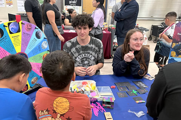 Students sit at a table with a colorful information wheel