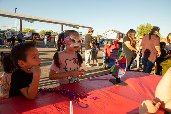 A little boy and a little girl wearing a masquerade mask play a spinning wheel game