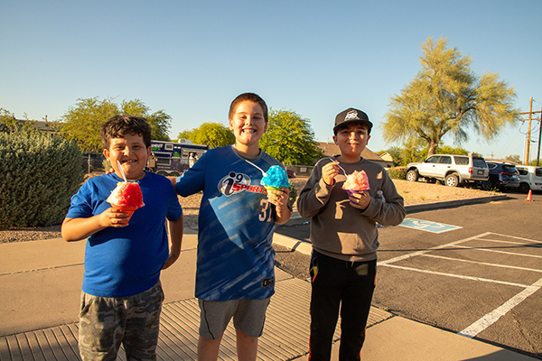 Three boys smile with their shaved ice treats