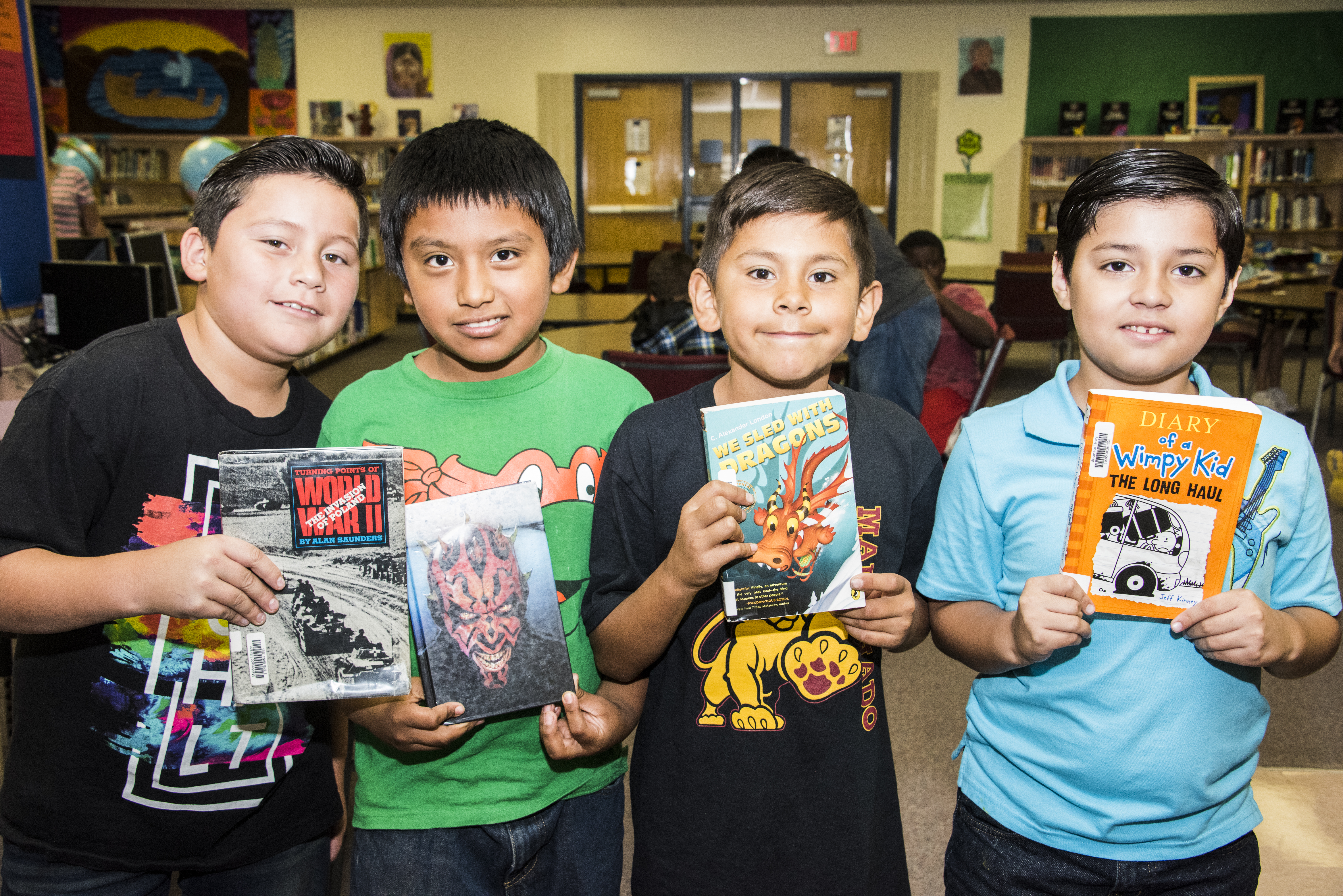 Four boys pose with their favorite books